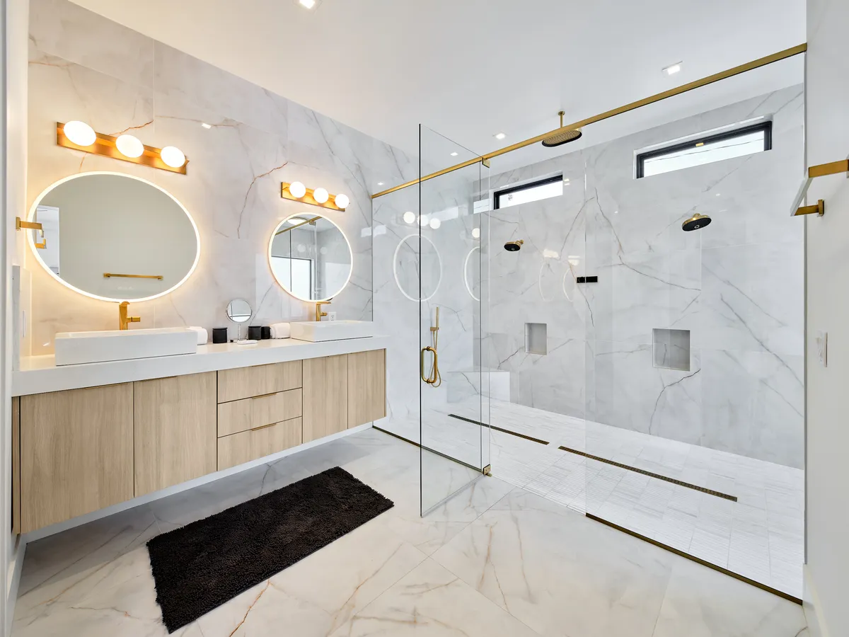 A sophisticated bathroom with double sinks, elegant faucets, large mirrors with warm lighting, and a spacious glass shower enclosure. The ambiance is serene, modern, and perfectly suited for daily relaxation and self-care rituals.