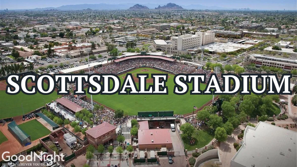 A vibrant exterior shot of a baseball field filled with spectators, with the surrounding cityscape and mountains visible in the background. The atmosphere is lively, capturing both the excitement of a game and the scenic desert environment.