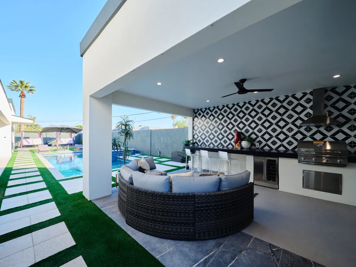 A stylish outdoor kitchen area adjacent to the swimming pool, complete with built-in barbecue, ample seating, and a spacious layout ideal for al fresco dining or group celebrations.