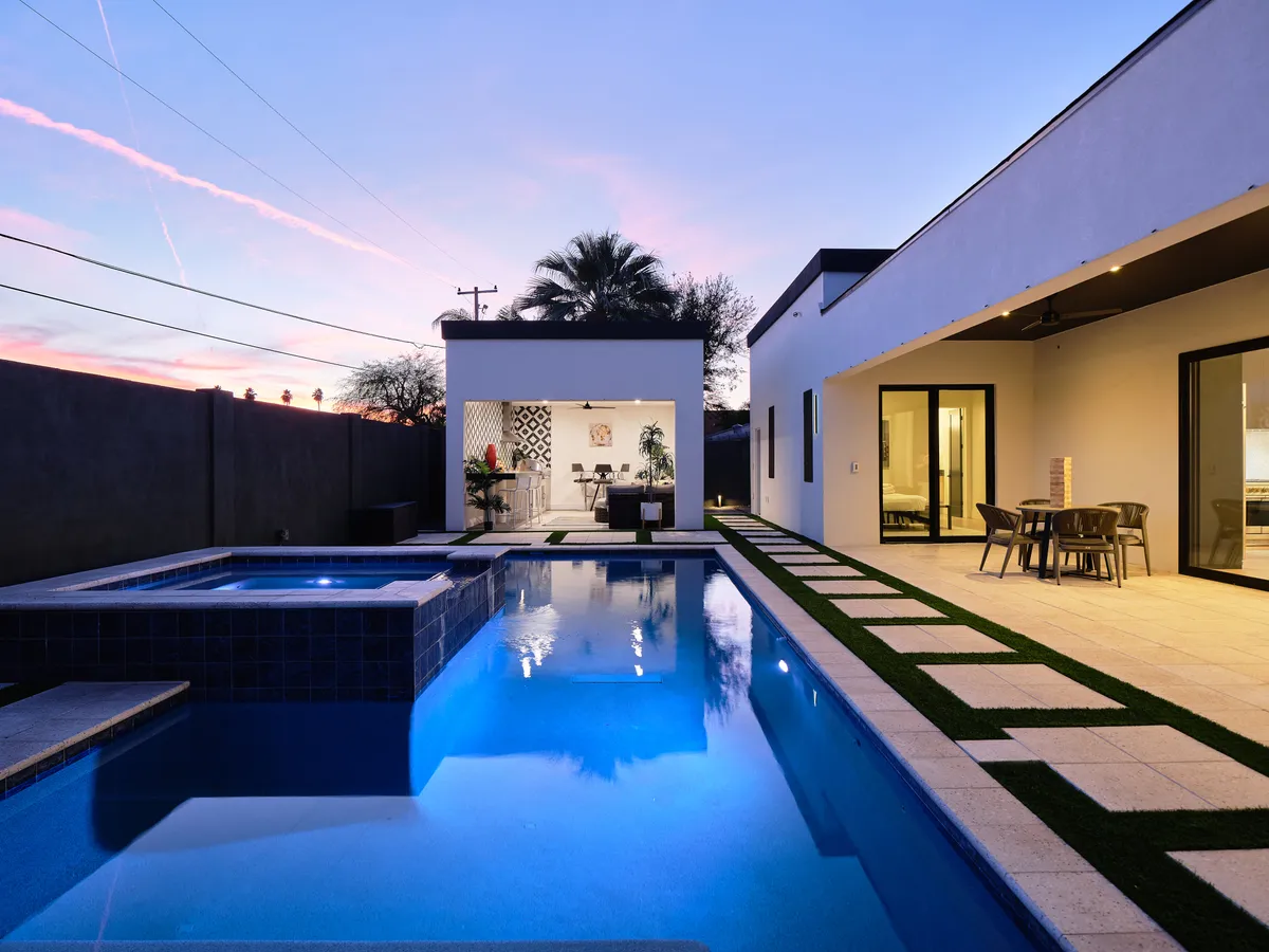 This exterior shot presents a serene swimming pool with a jacuzzi, dining area, and decorative wall, all set in a luxurious outdoor space. The setting is ideal for relaxation and hosting intimate gatherings, echoing the wellness and leisure opportunities described.