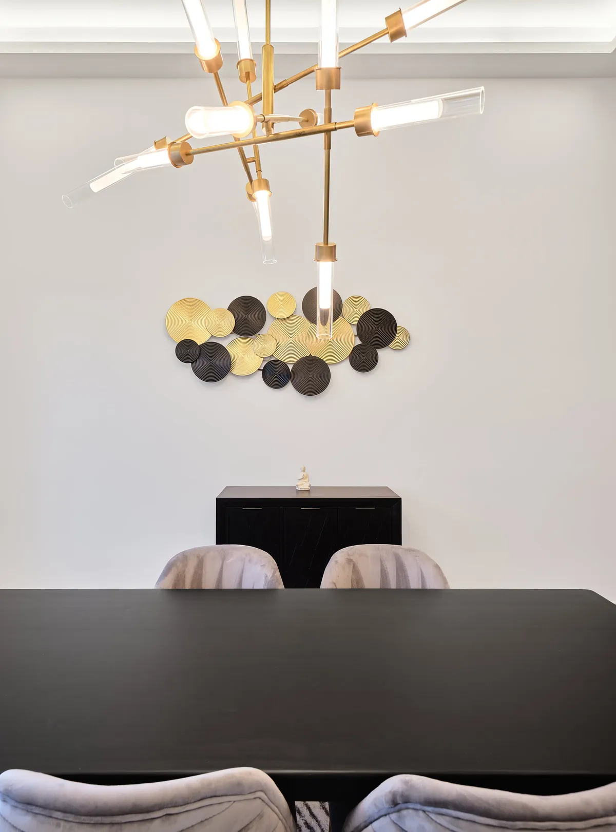 An elegant dining area with a modern chandelier above a stylish table, surrounded by eye-catching artwork and comfortable chairs. The mood is sophisticated and inviting, ideal for memorable meals or special celebrations.